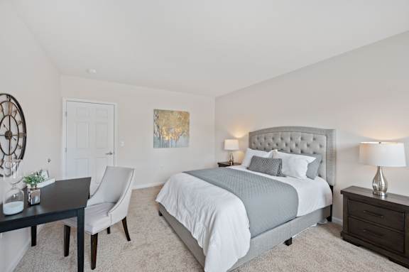A bedroom with a bed, nightstand, and chair. at Roebling Row, Covington, KY