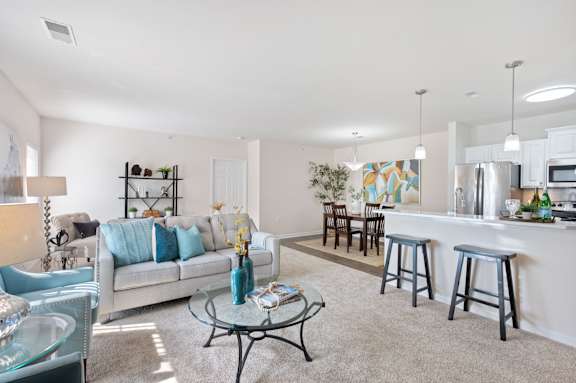 A living room with a couch, coffee table, and bar stools. at Roebling Row, Covington