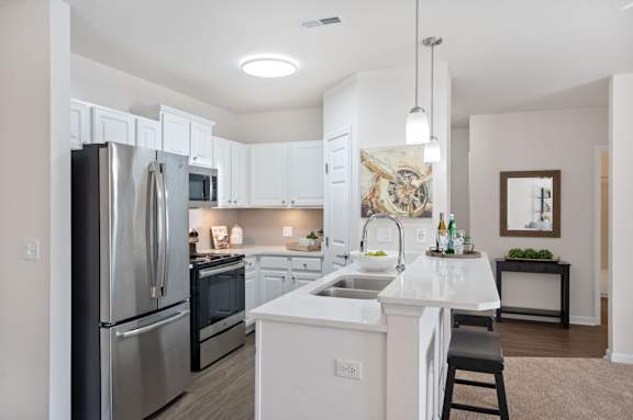 A modern kitchen with white cabinets and stainless steel appliances. at Roebling Row, Covington