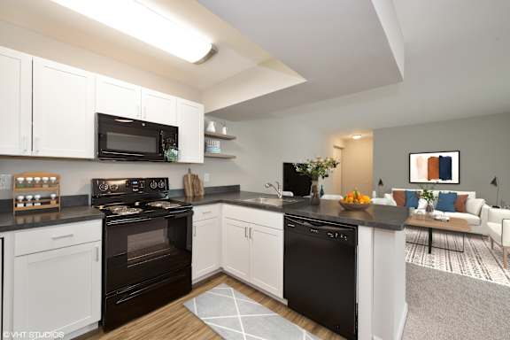 A modern kitchen with black and white appliances and cabinets. at 7 Pointe Apartments, Indianapolis, Indiana