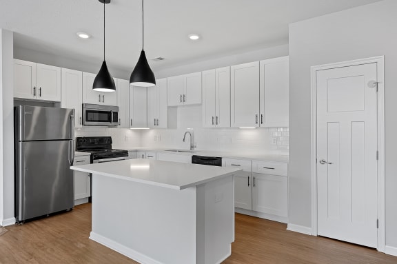 a large white kitchen with white cabinets and stainless steel appliances at Monmouth Row Apartments, Newport, Kentucky