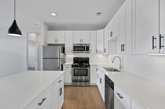 a large white kitchen with white cabinets and stainless steel appliances at Monmouth Row Apartments, Newport, Kentucky