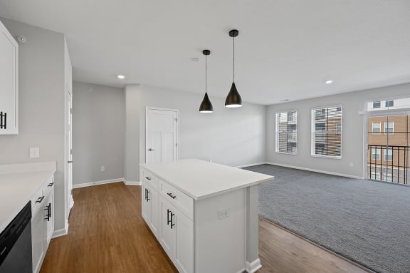 an open kitchen and living room with white cabinets and a white island with two lights at Monmouth Row Apartments, Newport, Kentucky