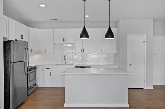 a large white kitchen with white cabinets and stainless steel appliances at Monmouth Row Apartments, Newport, KY