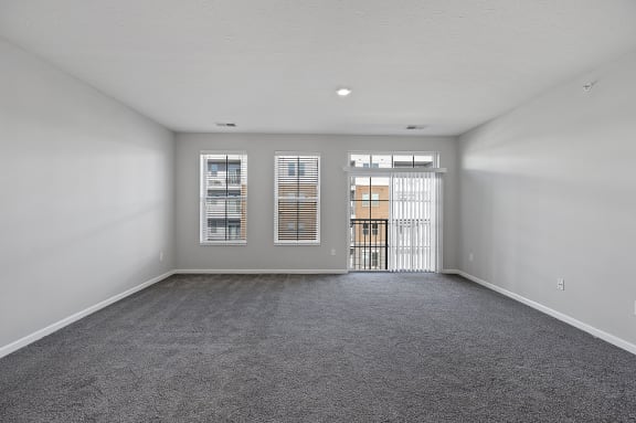 an empty living room with a door to a balcony at Monmouth Row Apartments, Newport, KY