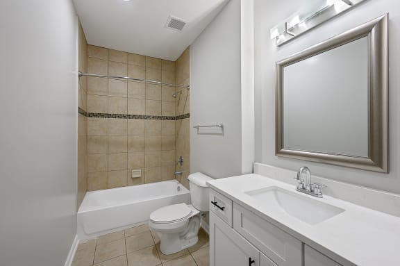 a bathroom with a sink toilet and tub and a mirror at Monmouth Row Apartments, Newport, KY, 41071