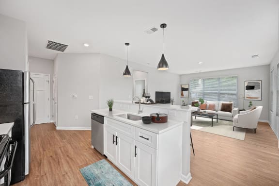 a white kitchen with an island and a living room at Monmouth Row Apartments, Newport, KY
