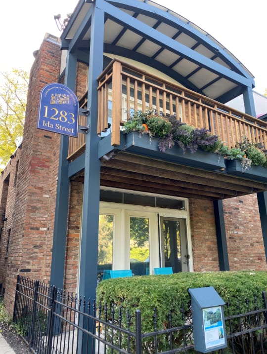 the front of a brick building with a balcony and a blue sign