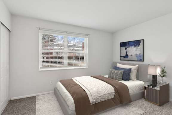 A bedroom with a bed, a nightstand, and a window with blinds.