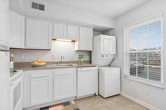 A white kitchen with a sink, stove, and refrigerator.