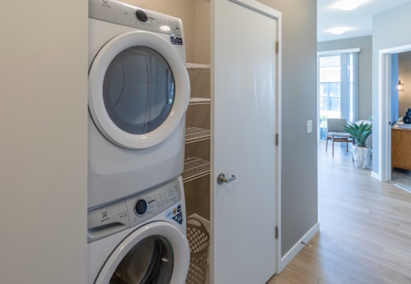 A white washing machine and dryer stacked on top of each other in a laundry room.