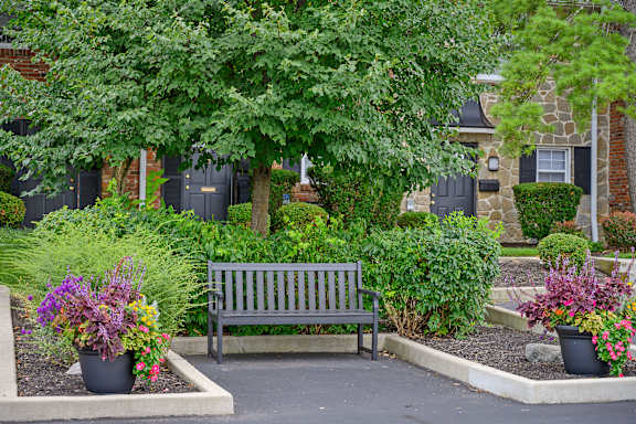 a wooden bench sitting in front of a garden at Olde Towne in Kenwood, Ohio