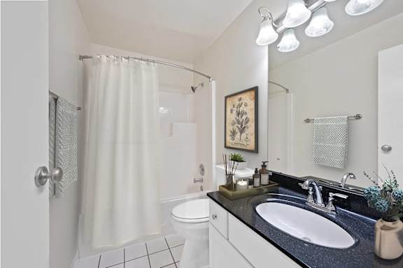 A bathroom with a white toilet, sink, and shower curtain. at Indian Creek Apartments*, Cincinnati