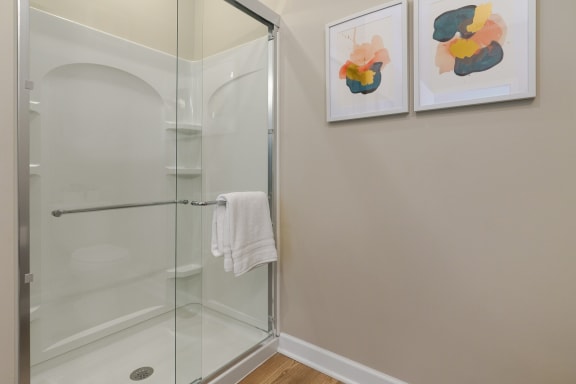 a bathroom with a glass shower and two paintings on the wall at Adelphi Quarter, Columbus, 43203