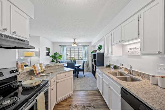A kitchen with white cabinets and a black stove top oven.