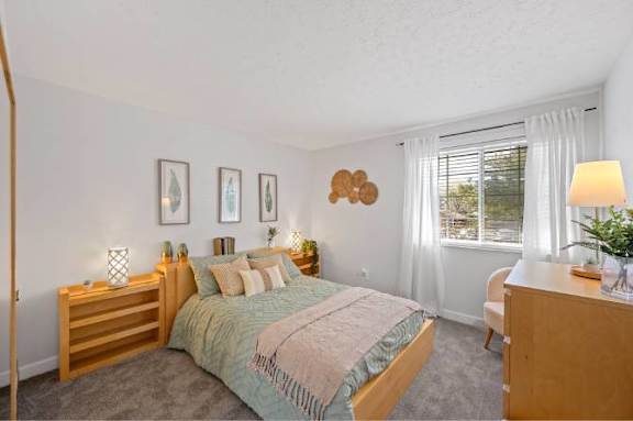 A bedroom with a bed, nightstand, and window.