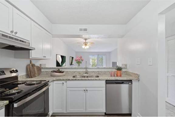 A kitchen with white cabinets and a granite countertop.