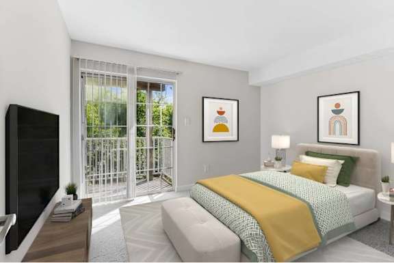 A bedroom with a bed, a couch, a television, and two framed pictures on the wall.