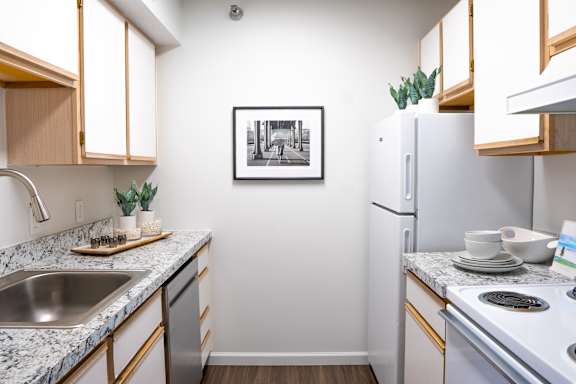 A kitchen with a fridge, stove, and sink.