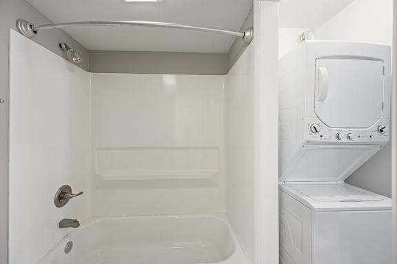 A white bathroom with a tub and a washer and dryer.