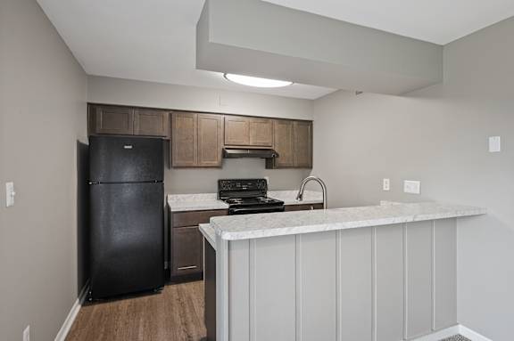 A kitchen with a black fridge and a white counter.