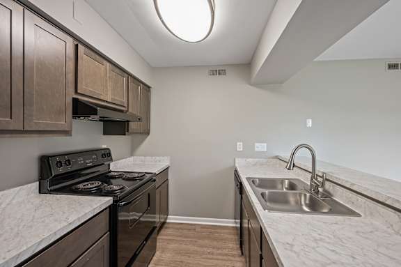 A kitchen with a black stove and a marble countertop.