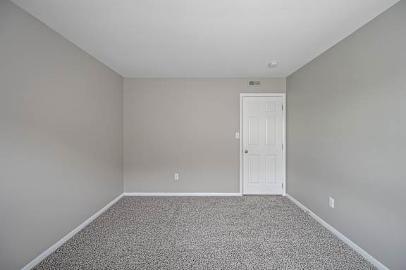 A room with a white door and carpeted floor.
