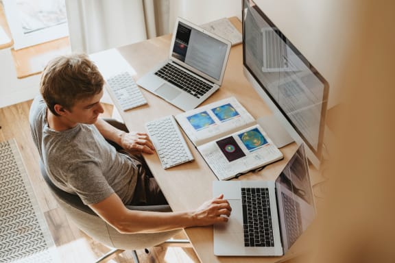 Man sitting at a desk with three laptops and a tablet  at Indian Lookout, Ohio, 45449