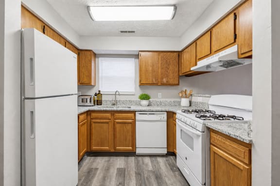 A kitchen with white appliances and wooden cabinets.
