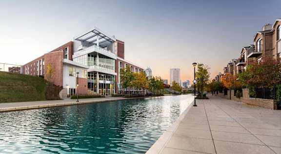 A modern building with a glass facade is situated next to a body of water.