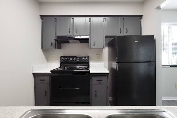 A black stove and oven in a kitchen with a black fridge.