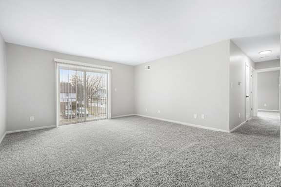 A spacious room with grey carpeting and white walls.