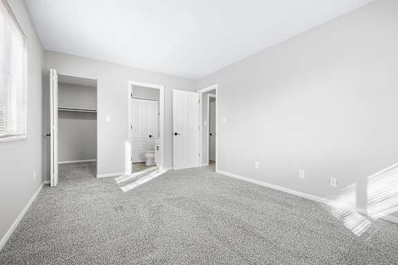 A spacious room with grey carpeting and white walls.