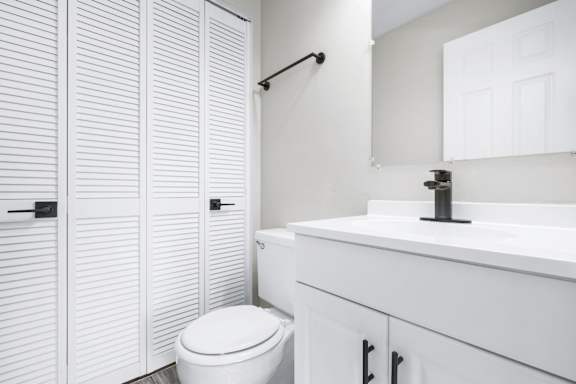 A white toilet sits next to a white sink in a bathroom.