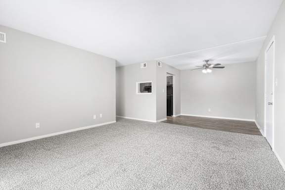 A spacious room with a ceiling fan and carpeted floor.