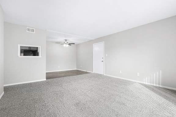 A spacious room with a carpeted floor and a ceiling fan.