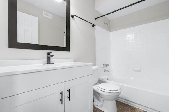 A white bathroom with a toilet, sink, and mirror.