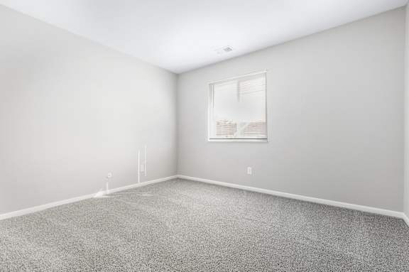 A room with a carpeted floor and a window.