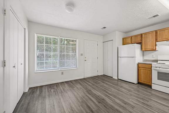 A kitchen with white appliances and wooden cabinets.