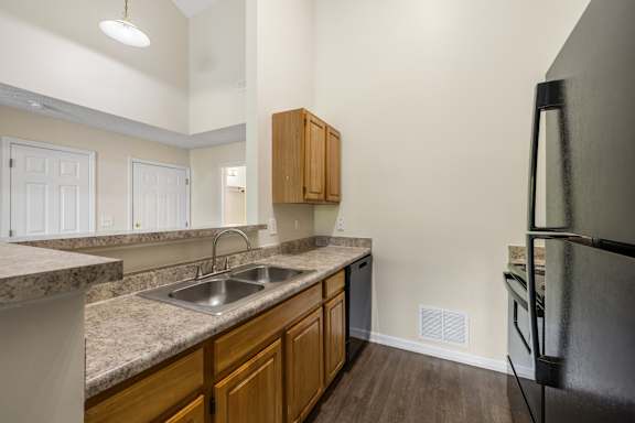 A kitchen with a sink, refrigerator, and cabinets.
