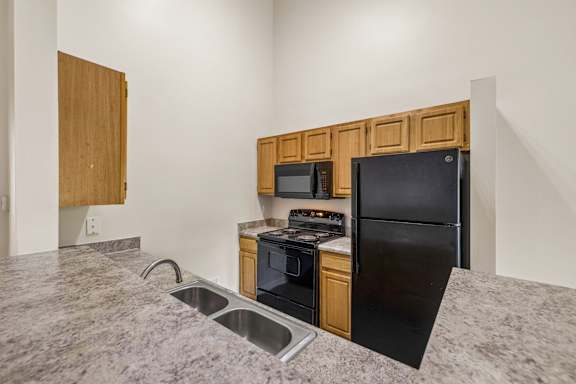 A kitchen with black appliances and wooden cabinets.