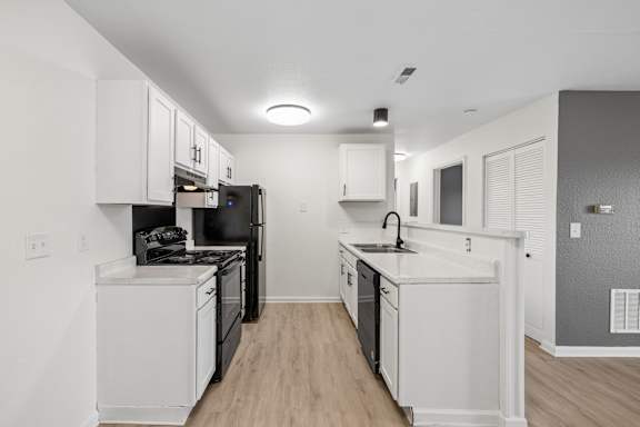 A kitchen with black appliances and white cabinets.