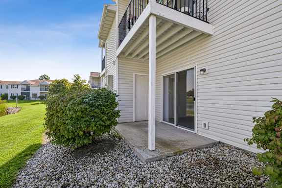 A house with a balcony and a bush in front.