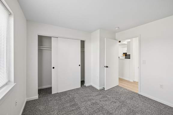 A room with white walls and a grey carpet.