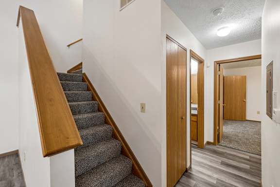 A staircase with a wooden handrail and a carpeted floor.