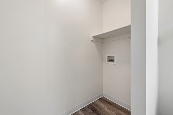 A white wall with a picture frame and a wooden floor.