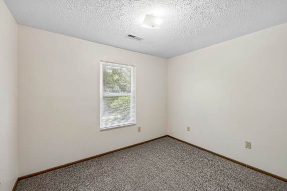 A room with a window and carpeted floor.