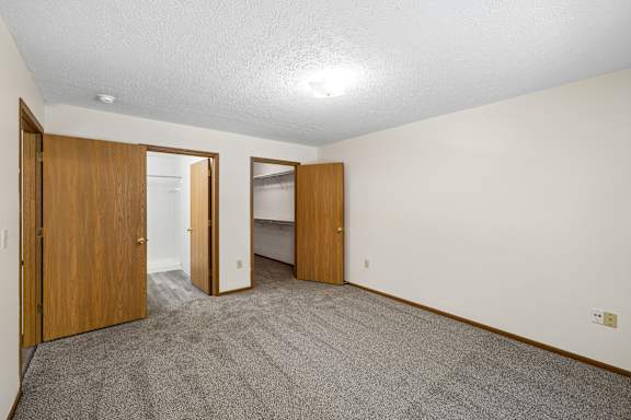 A room with carpeted floor and three doors.