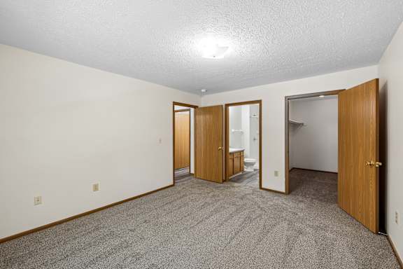 A room with carpeted floor and three doors.