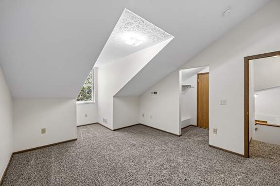 A spacious room with a skylight and carpeted floor.